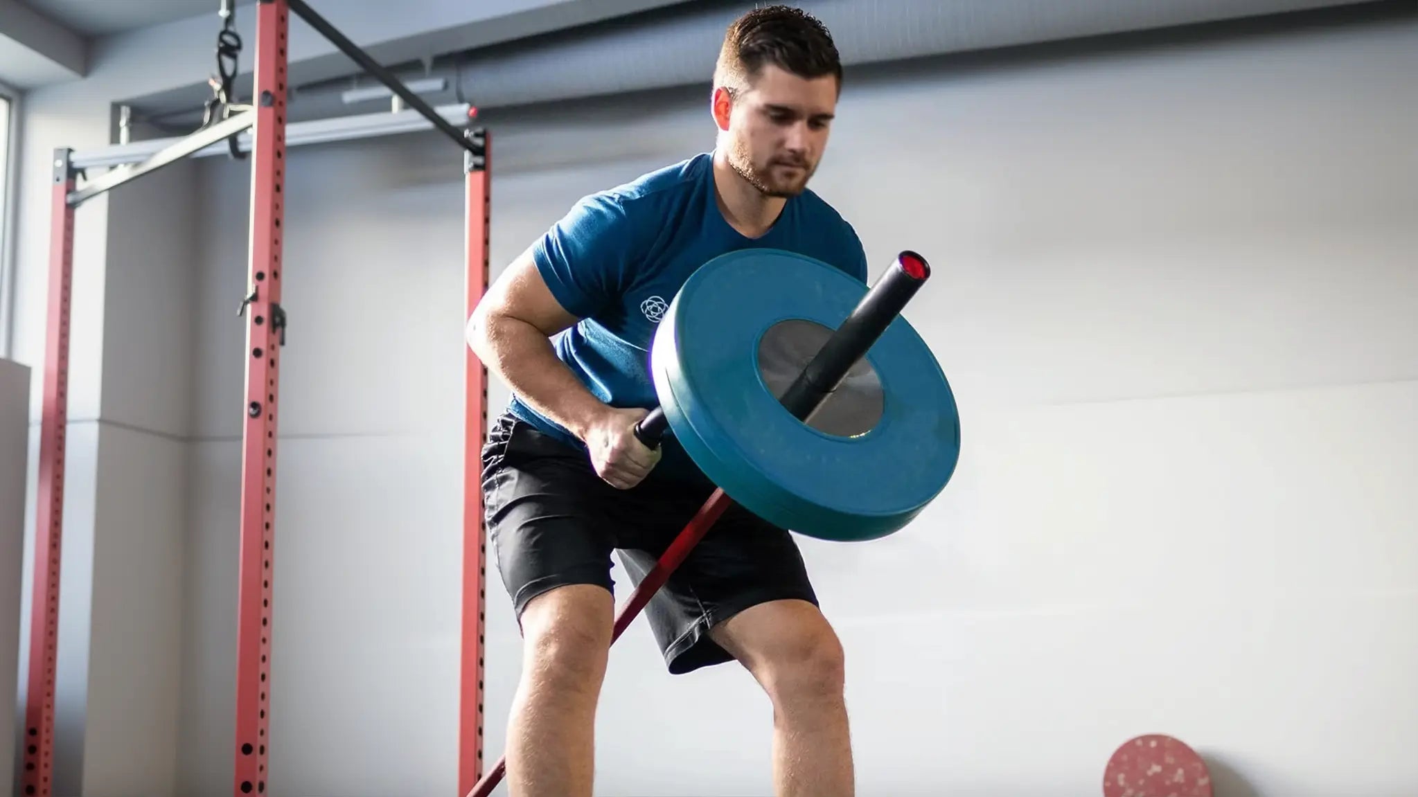 Person performing a landmine deadlift with the double arm handle and barbell anchored to a rack, emphasizing 360-degree rotational and core strength training.