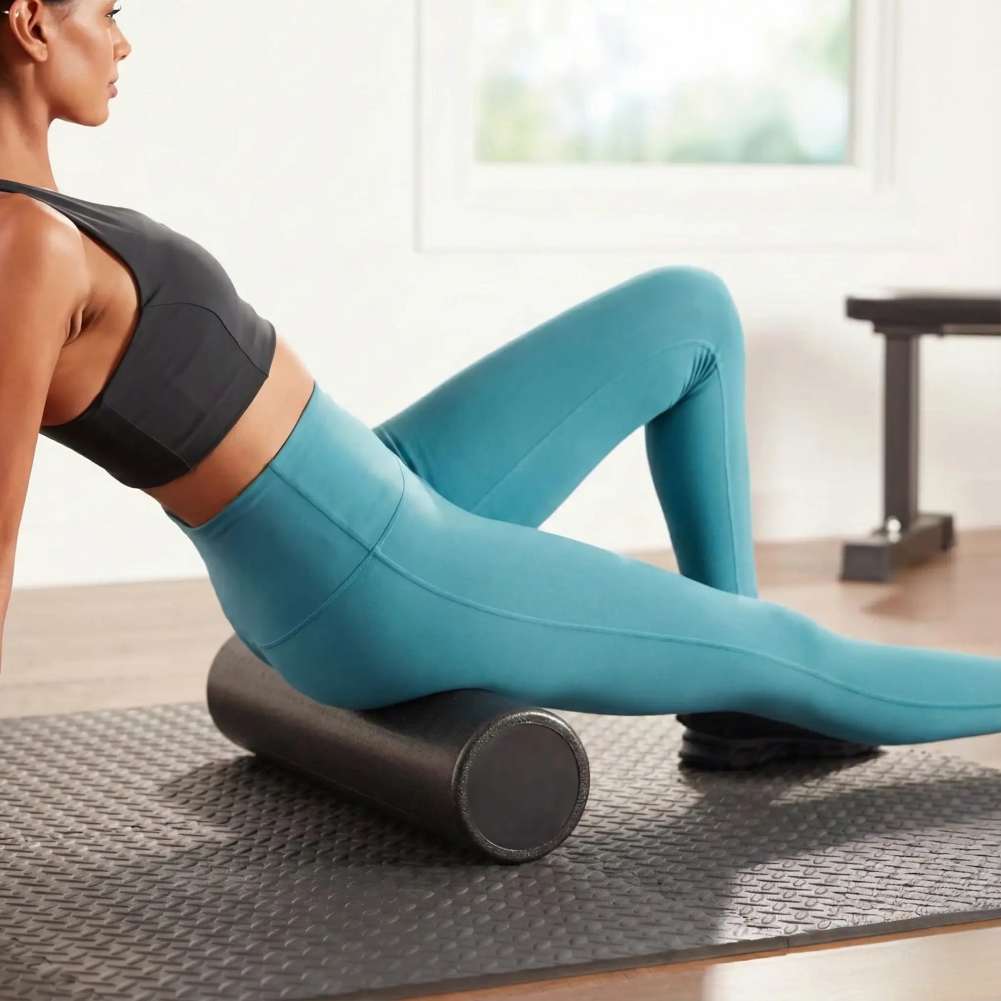 Woman using a high-density foam roller on her glutes and hamstrings.