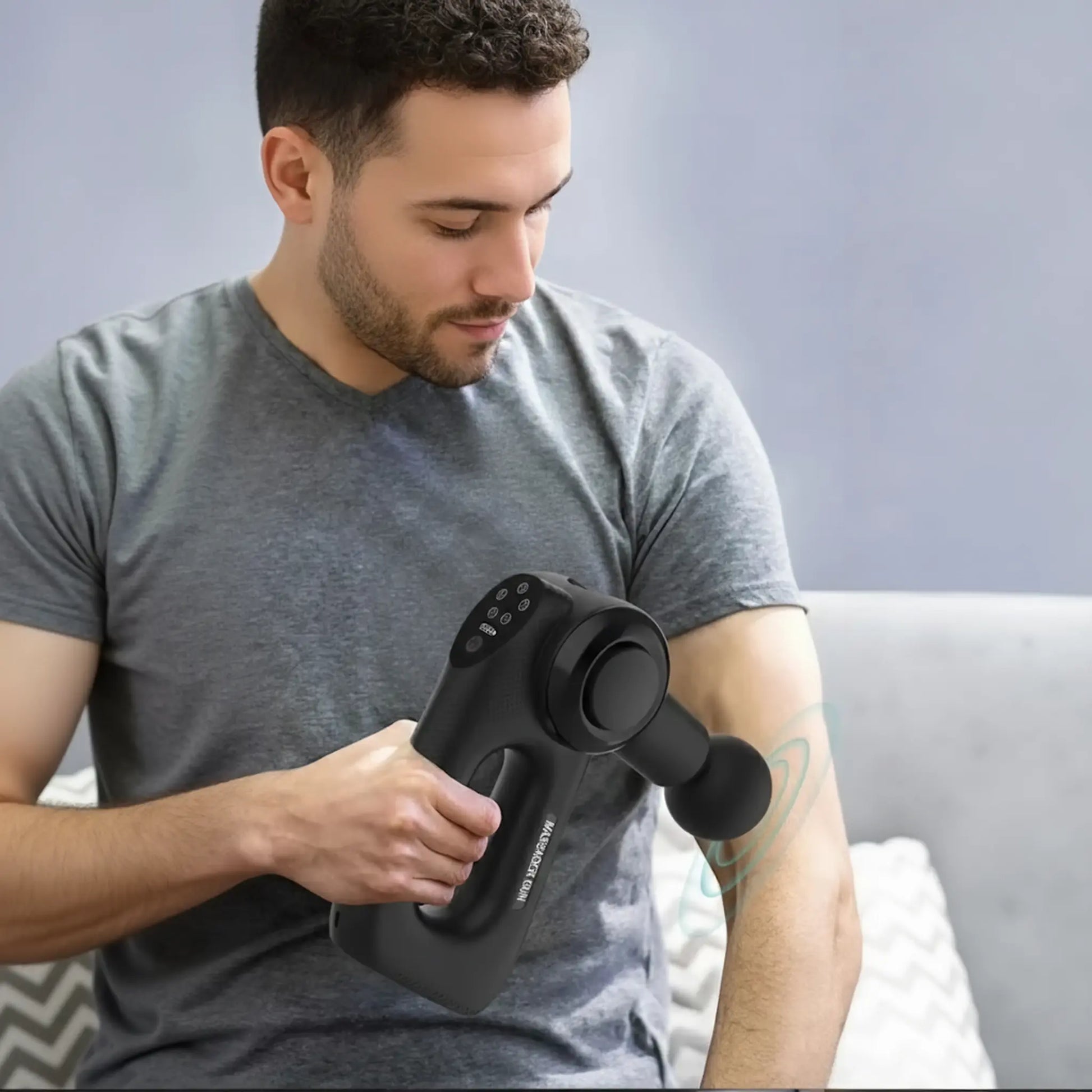 Man using portable massage gun on arm for post workout muscle recovery