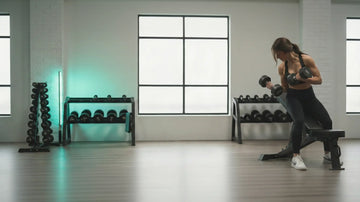 Woman exercising with dumbbells in a home gym setting