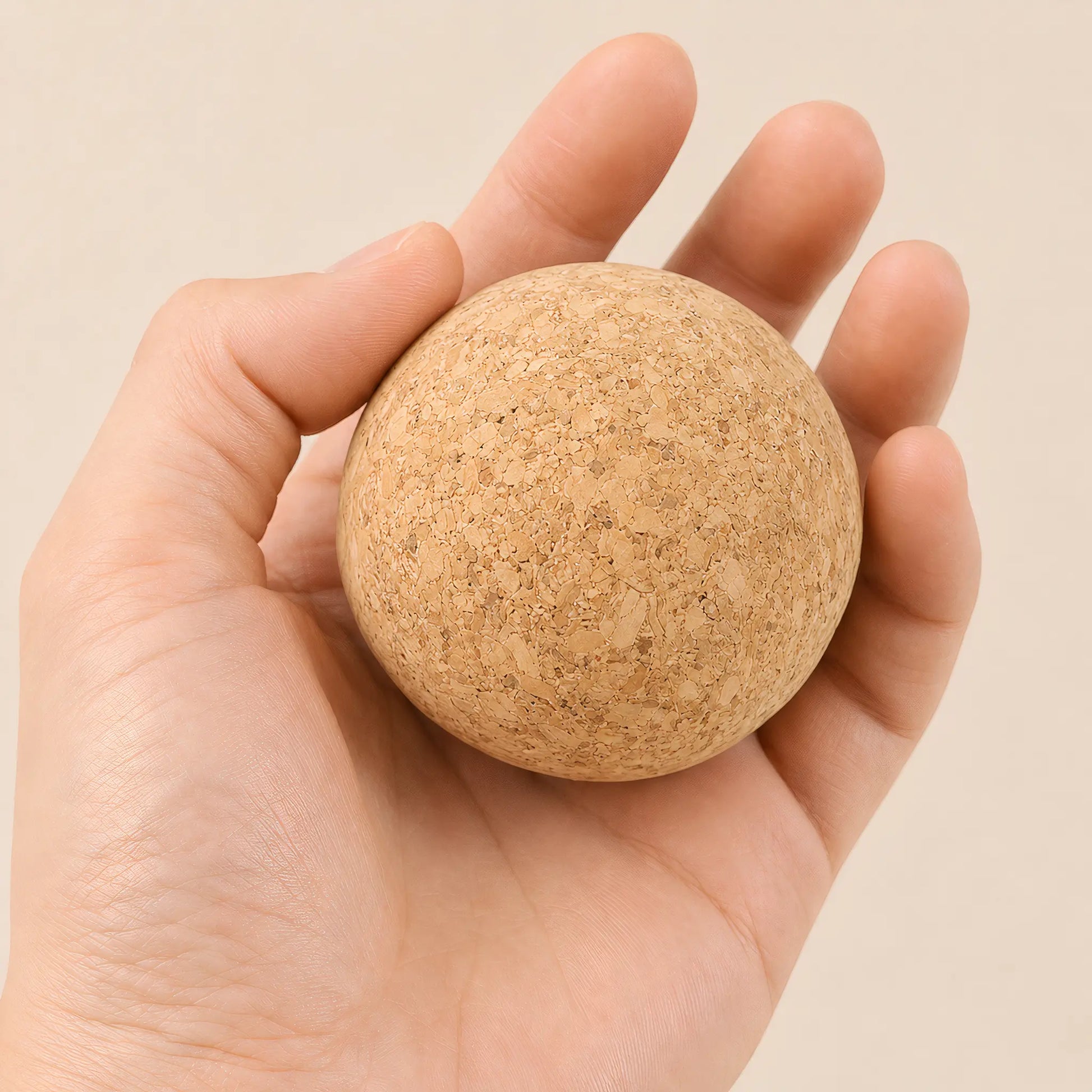 Hand holding cork massage ball for trigger point and muscle recovery work