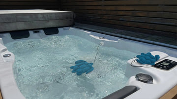 Blue turtle-shaped scum absorbers floating in a bubbling hot tub to absorb body oils and keep spa water clean.
